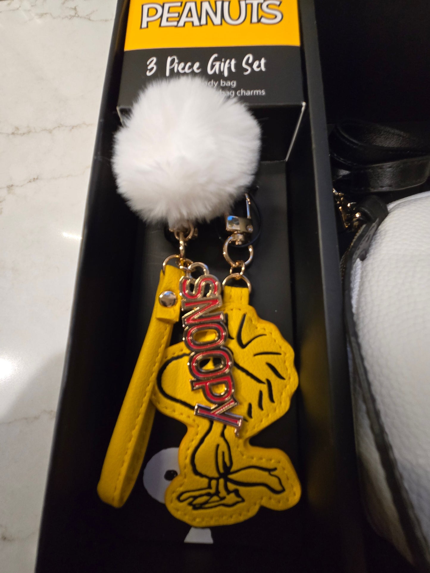 Snoopy keychain with white pom-pom on a Peanuts branded gift set packaging.