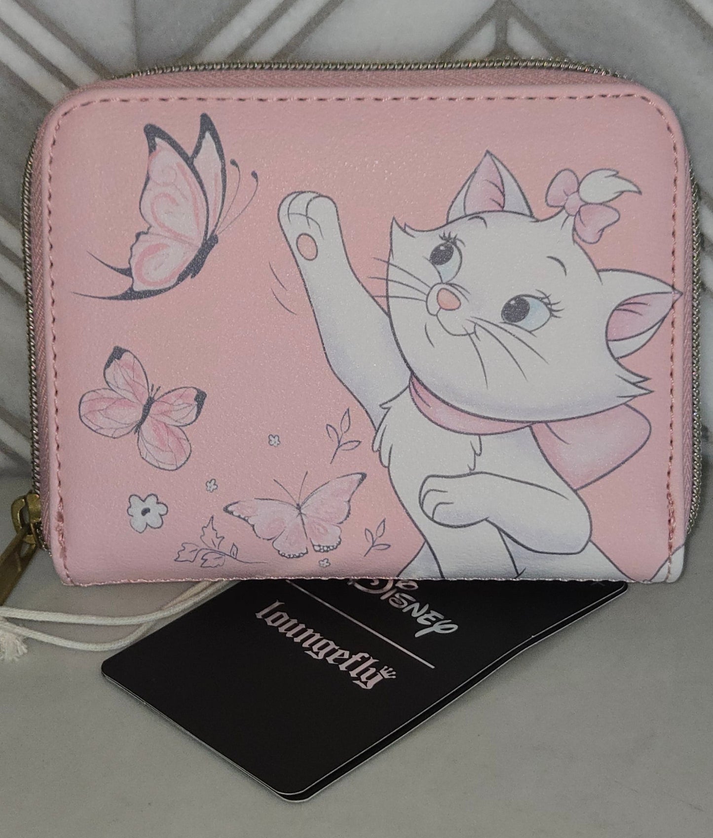 Pink wallet with cartoon cat design on a gray surface